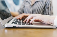 Foto de mãos sobre o teclado de notebook